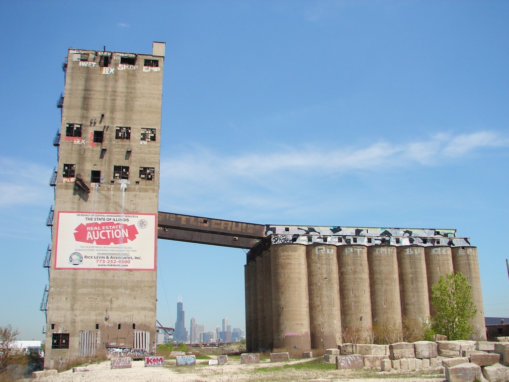 Santa Fe Grain Elevator in Chicago with downtown skyline show in the distance between structures, blue sky above