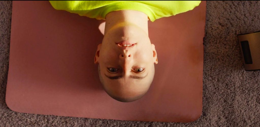 Photo of person with shaved head staring up into the camera.
