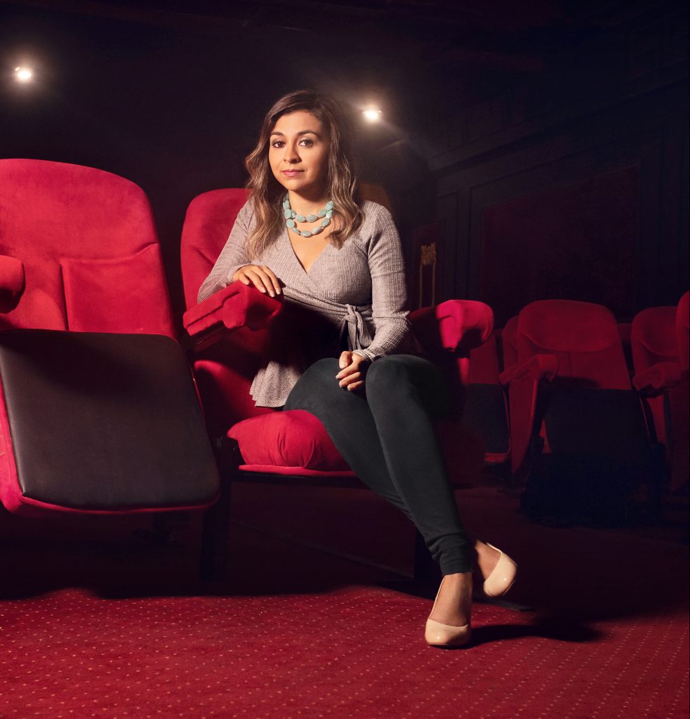 Colette Ghunim poses in a red movie theater chair.