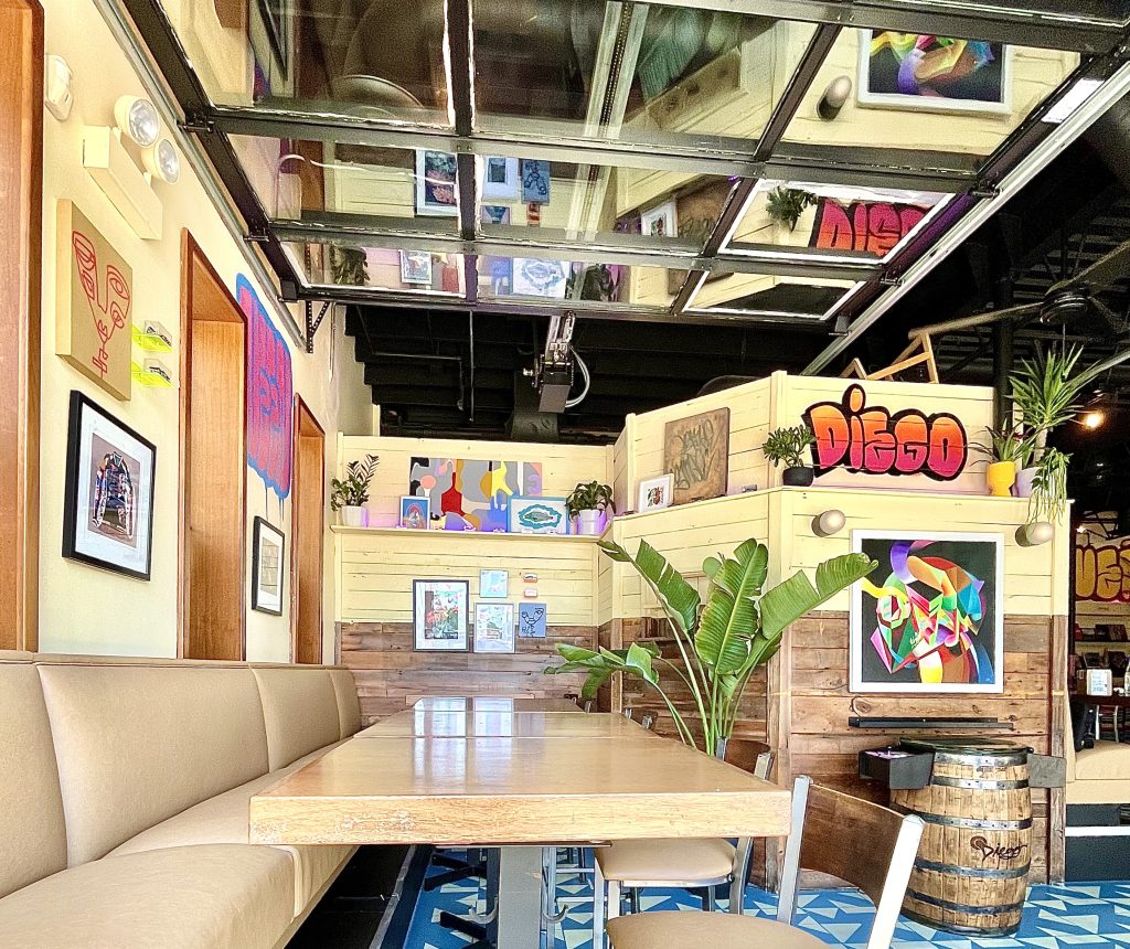 Interior restaurant space with beige booths and artwork on walls and shelves.
