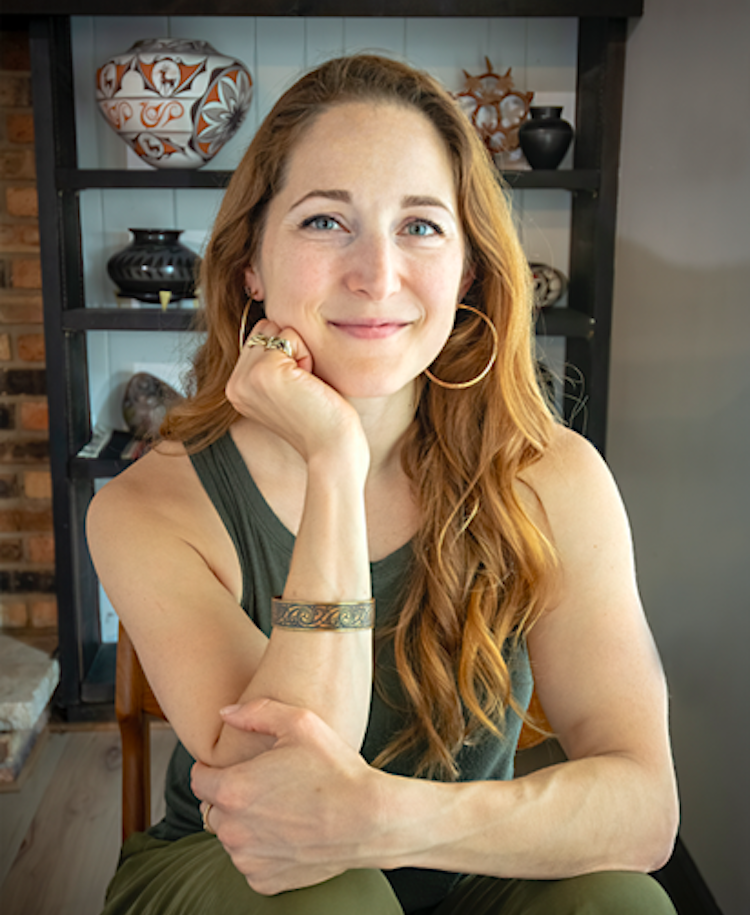 Portrait of smiling woman sitting with head resting on arm.