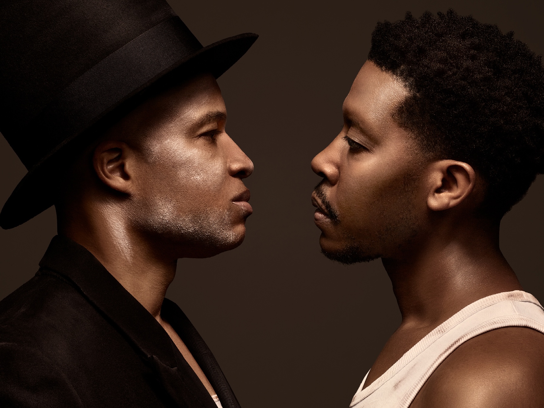 Two actors face one another with dark background